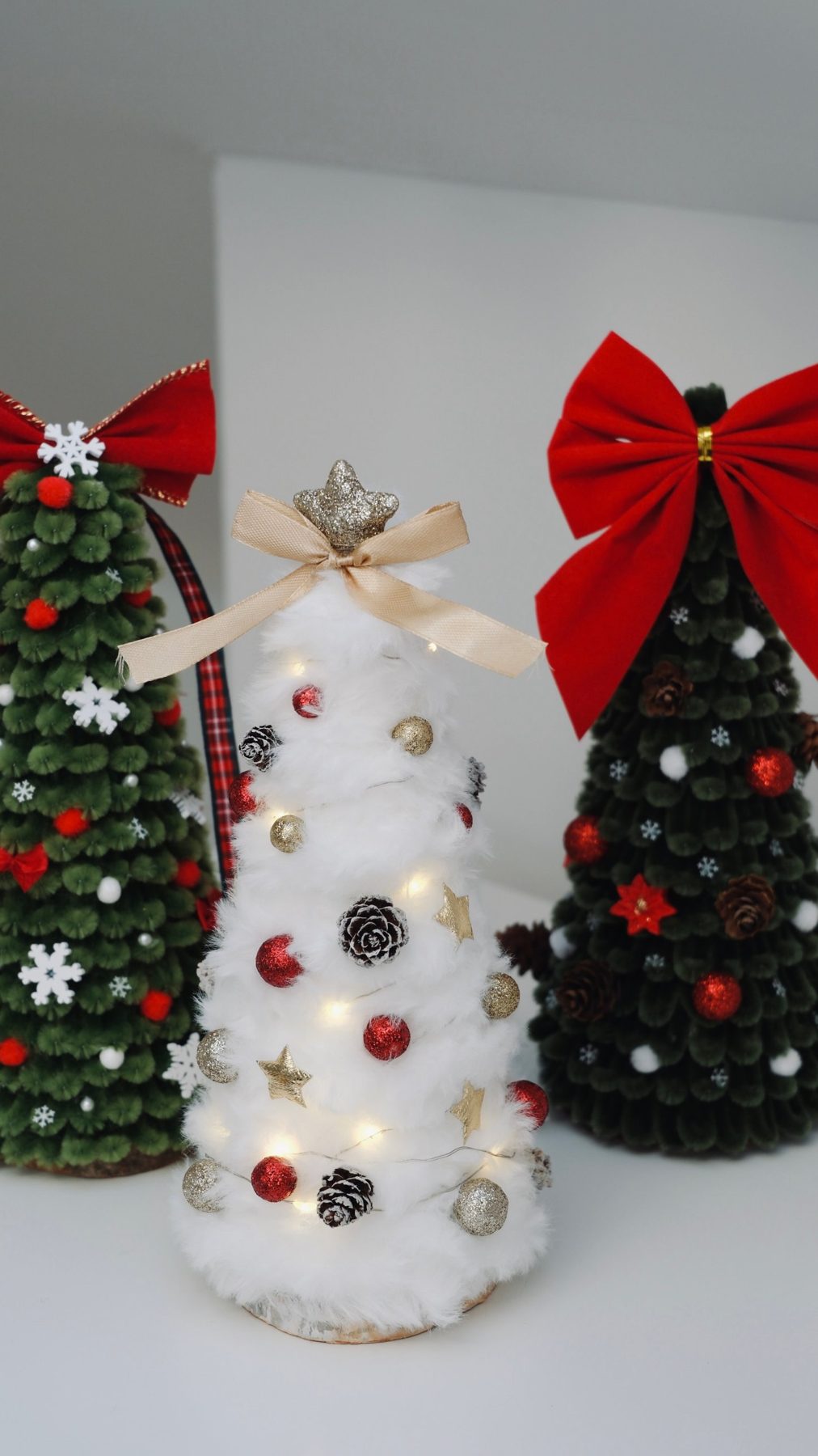 Flauschiger weißer Baum mit Lichterkette, goldenen Sternen und Zapfen